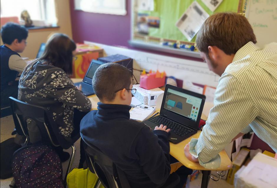 Teacher looking at TinkerCAD design on a student laptop.